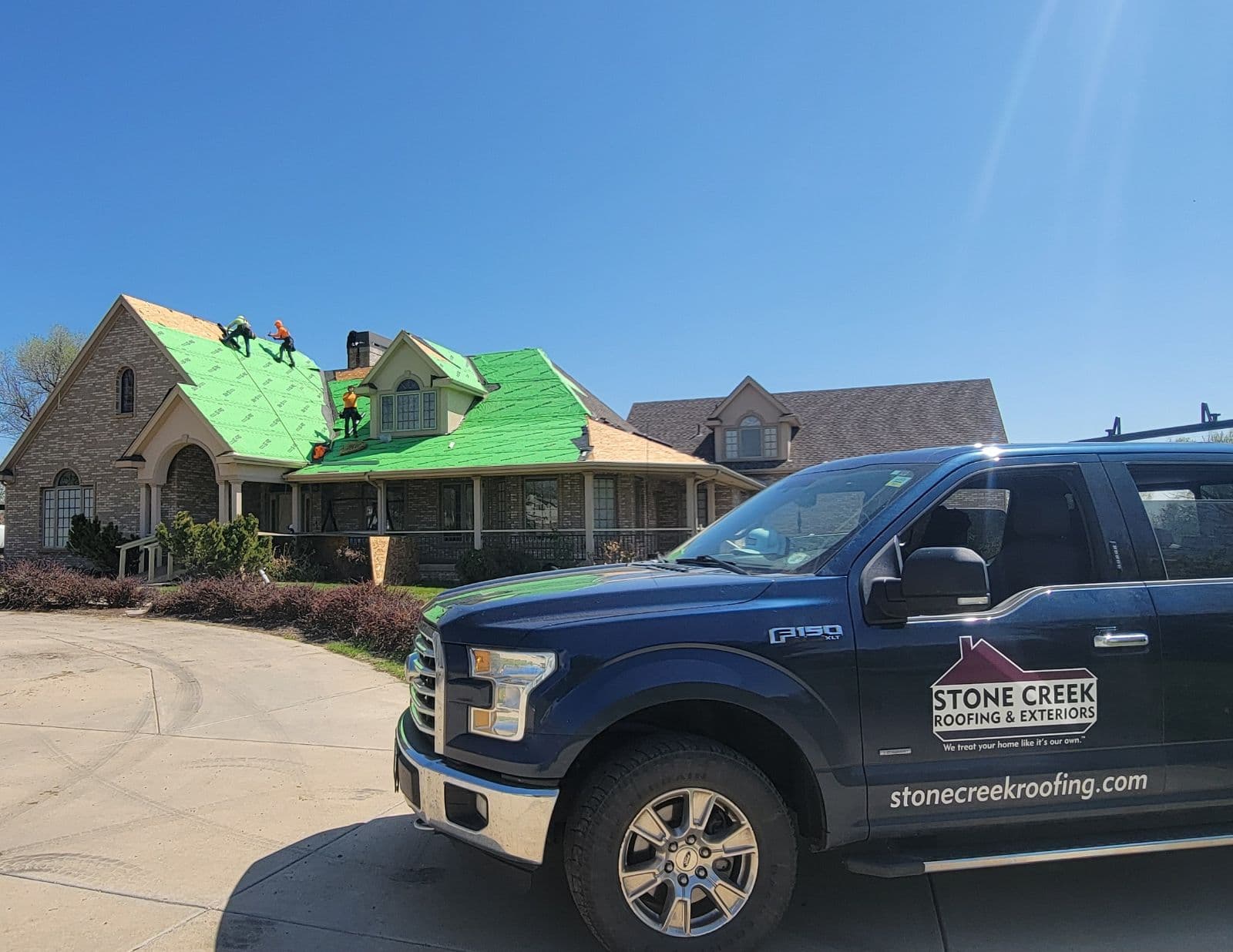 Ford truck in fron of roofers replacing roof