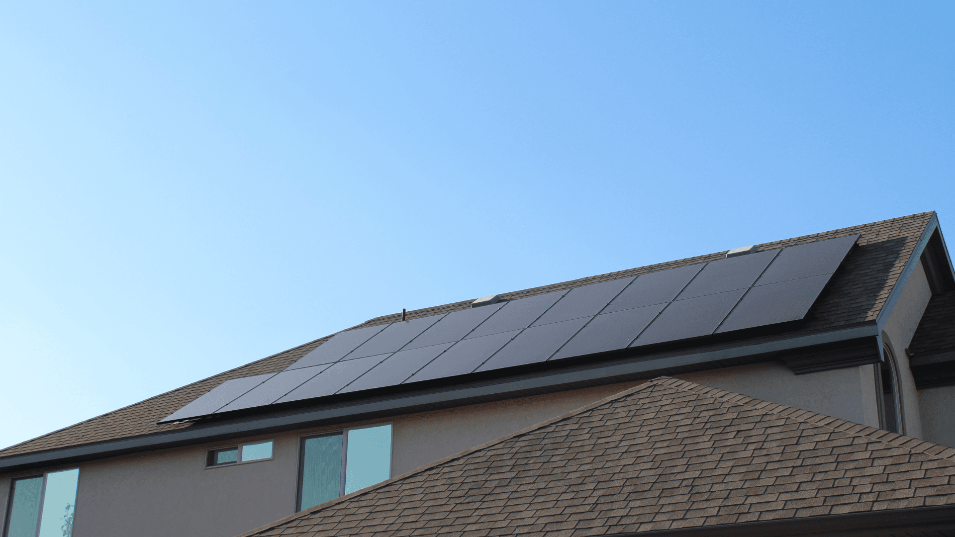 solar panels on roof with brown shingles and blue sky