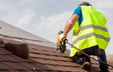 Man nailing roof tiles into roof
